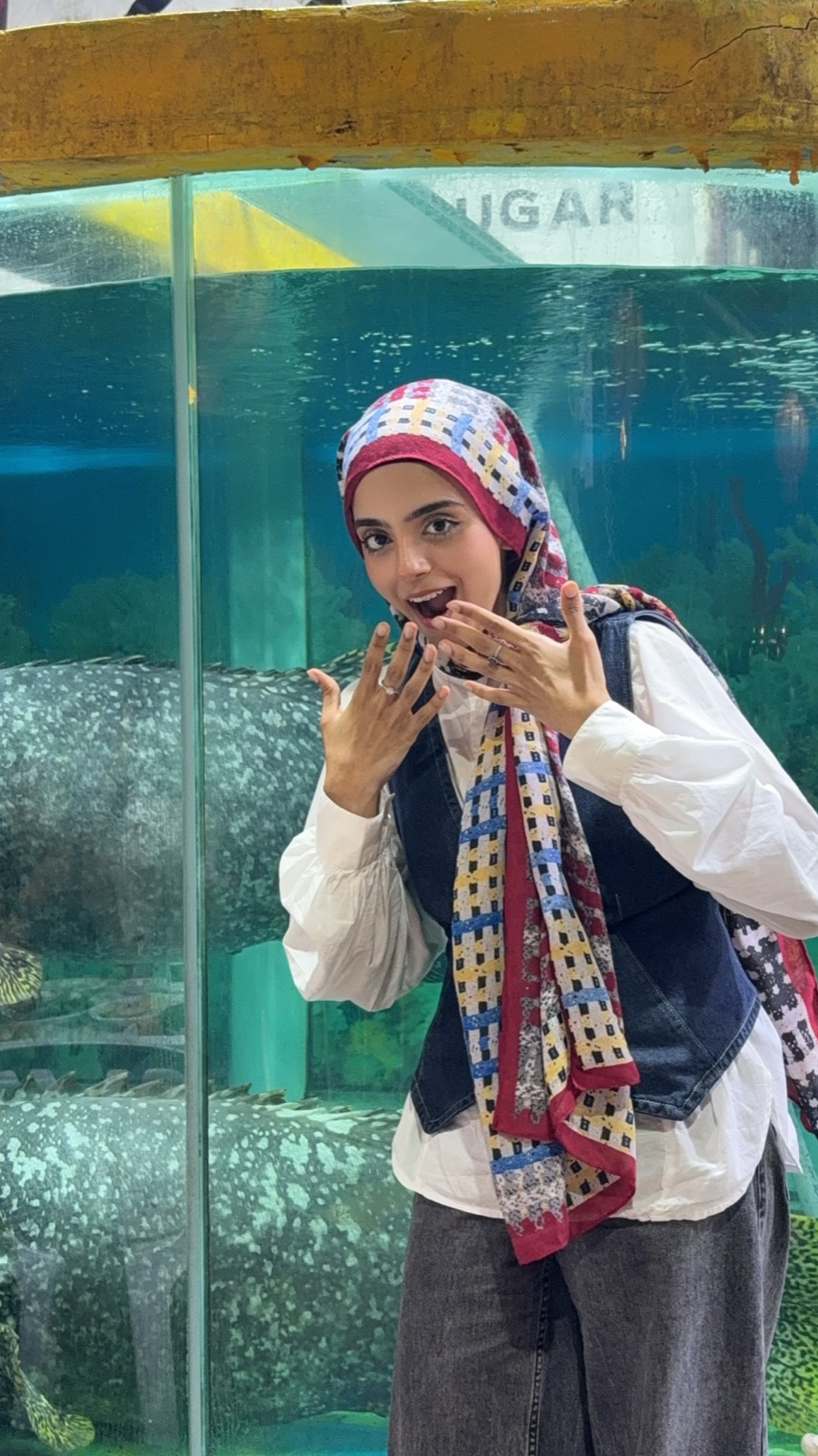 Eman reacting delightedly in front of a large aquarium